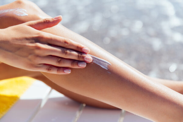 close-up-view-female-hand-applying-sunscreen-her-leg-near-sea (1)